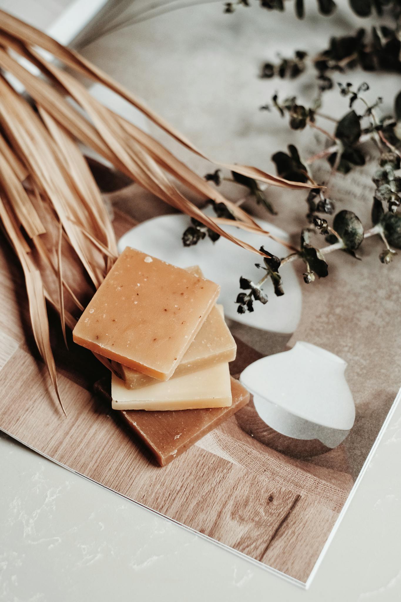 Artistic display of organic soap bars with dried leaves and eucalyptus for a natural touch.
